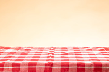 An empty table with a red checkered tablecloth and an bright background. For your food and product display montage.