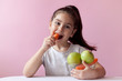 © kaganskaya115 - A cute little girl eating fresh vegetables. A portrait on pastel background. Healthy teeth.