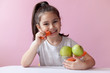 © kaganskaya115 - A cute little girl eating fresh vegetables. A portrait on pastel background. Healthy teeth.