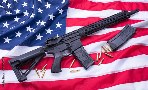Custom built AR-15 carbine, bullets and a magazine on American flag surface, background. Studio shot.