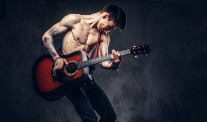 Handsome shirtless young musician playing guitar while jumping.