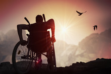 Disabled Handicapped Man Has A Hope. He Is Sitting On Wheelchair And Stretching Hands At Sunset.