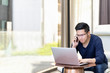 © ChayTee - Asian man creative freelancer waer glasses using mobile phone and looking at computer laptop. Candid serious young entrepreneur call phone and checking information on network at modern office.