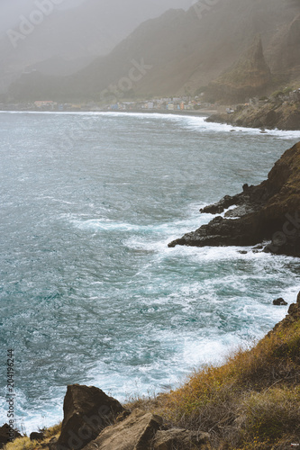 Poster Rough ocean waves with blowing spray rolling onto the rocky volcanic shore