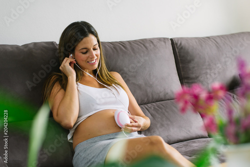 Cuadros en Lienzo Happy pregnant woman using fetal droppler device for listening her baby heartbeat