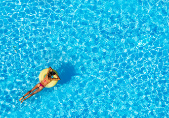 Wall Mural - Slim woman floating on air ring in the pool