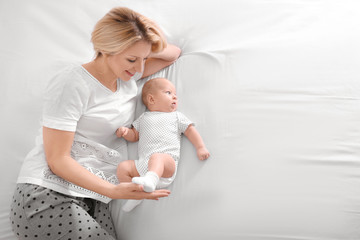 Poster - Young mother and her baby lying on bed at home