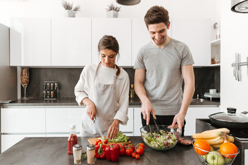 Wall Mural - Portrait of a happy young couple cooking salad