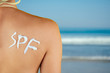 © yurakrasil - an inscription with a cream of spf on the back of a girl in a swimsuit on against the sea