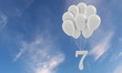 Number 7 party celebration. Number attached to a bunch of white balloons against blue sky