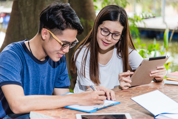 Wall Mural - Man students and girlfriend are during reading information from tablet and book outdoor