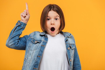 Portrait of an excited little schoolgirl pointing finger up