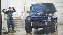 Worker In Auto Service Is Washing A Luxury Car In The Suds By Water Hoses