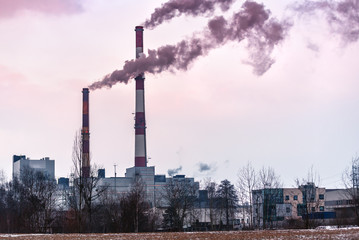 two factory pipes with smoke on sunset