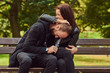 © Fxquadro - Attractive modern couple sitting on a bench in a park.