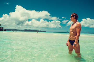 Caucasian man look into the distance enjoying summer beach vacation. Time to travel. Stress free. Shirtless fit athletic male body. Exotic luxury holiday. Tourism concept. Copy space. Wear swimsuit