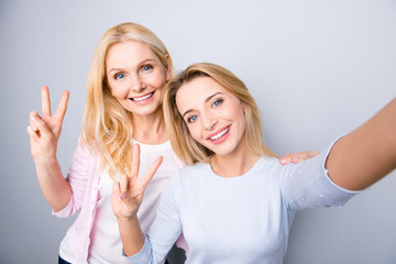 Canvas Print - Self portrait of charming pretty stylish positive cheerful mom and adult child shooting selfie on front camera gesturing v-sign with two fingers isolated on grey background rest relax leisure concept