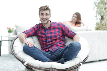 Wall Mural - modern young man sitting in a big round chair on blurred background