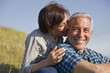 © Erickson Stock - Smiling mid-adult woman nibbling on her husbands ear while sitting together in the country.