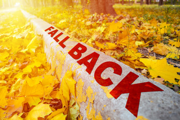 Fall Time Change concept. Yellow Leaves and words Fall Time on cement border in autumn park. Perspective, Diagonal