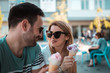 © Nebojsa - Happy couple with sunglasses eating ice cream while sitting outside on a sunny day.