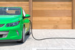 Modernes Elektroauto in grün tankt zu Hause Strom frontale Perspektive