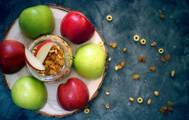 Red and green halves of apples on a wooden chair on a table next to breakfast cereals