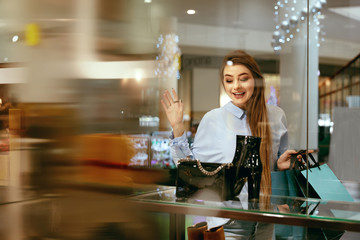 Wall Mural - Young Woman Looking Through Shop Window