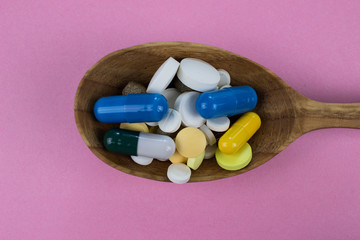 Capsules and tablets on wooden spoon. Medicine pharmaceutical theme. 