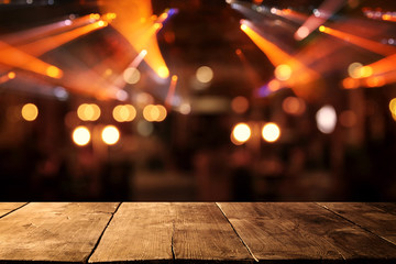 Image of wooden table in front of abstract blurred restaurant lights background.