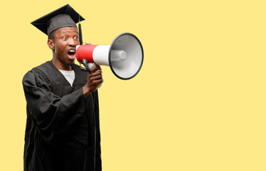 young african graduate student black man communicates shouting loud holding a megaphone, expressing 