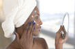 © JPC-PROD - Portrait view of beautiful african american young woman getting ready in home bathroom , applying moisturising cosmetics, cream, mirror face reflection,