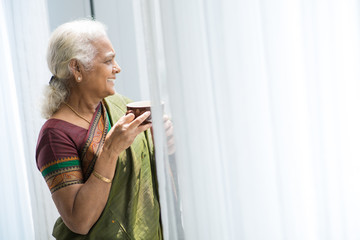 Wall Mural - Aged woman looking throug window