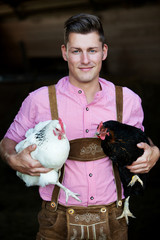 young bavarian man holding two chickens