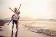 © Mediteraneo - Happy couple in love on beach summer vacations. Joyful girl piggybacking on young boyfriend having fun.