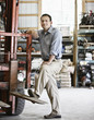 © Mint Images - Owner of landscape company leaning on forklift