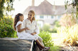 © Erickson Stock - Young girl sits on a footbridge talking to her grandmother.