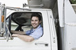 © Mint Images - Caucasian man truck driver in company truck window.