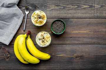 Wall Mural - Light fruit dessert for slimming. Banana pudding with superfood chia seeds on dark wooden background with blue tablecloth flat lay copy space