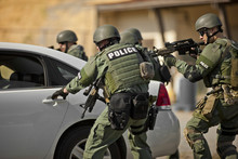 Group Of Police Officers Surround A Vehicle During An Exercise At A Training Facility.