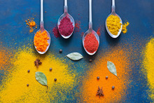 A Variety Of Multicolored Spices With Spoons On A Blue Background. Top View, Copy Space.