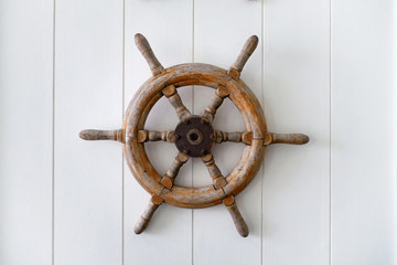 Old boat steering wheel mounted on the white wall