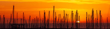 Silhouettes Of Yacht Masts, Orange Sunrise In A Port Panorama