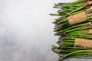 Wall Mural - Green fresh asparagus on gray background. Top view. Raw, vegan, vegetarian and clean eating concept.