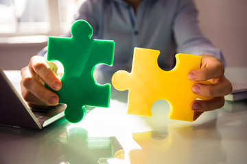 Businessperson's Hand Holding Two Jigsaw Puzzle