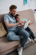 © LIGHTFIELD STUDIOS - father and little son using tablet together on sofa at home