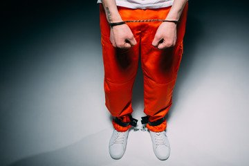 Cropped view of man wearing orange pants in cuffs on dark background