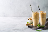 Iced coffee in tall glasses with cream and pieces of sugar, mint and straw