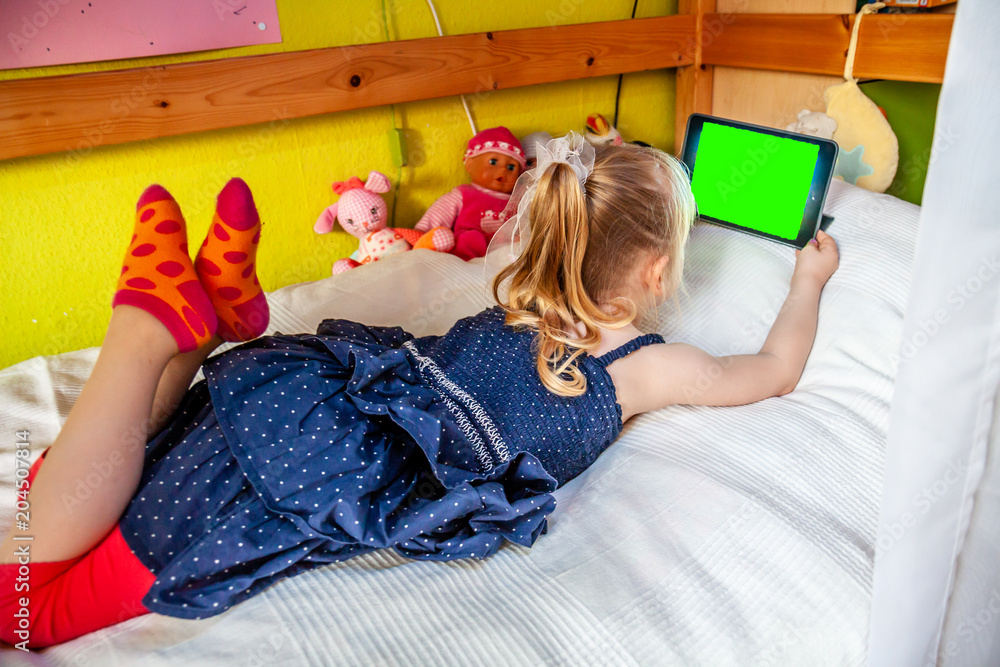 Cute little girl lying on bed and using her tablet computer Stock Photo ...