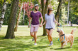 Young couple walking their dog together in the park during summer